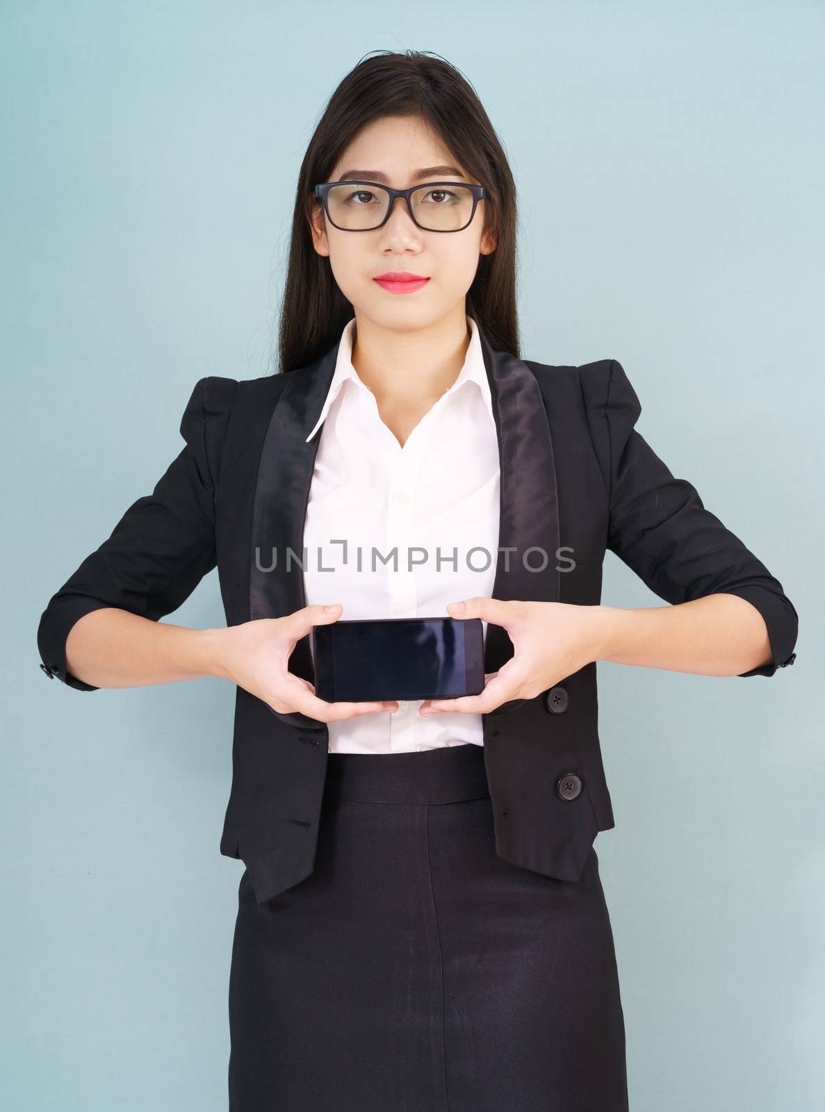 Young women in suit holding her smartphone standing against blue background