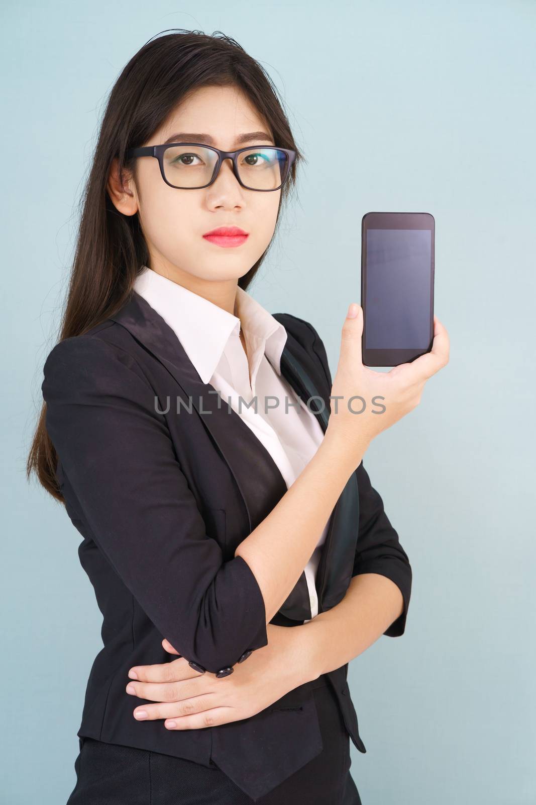 Young women in suit holding her smartphone standing against blue background