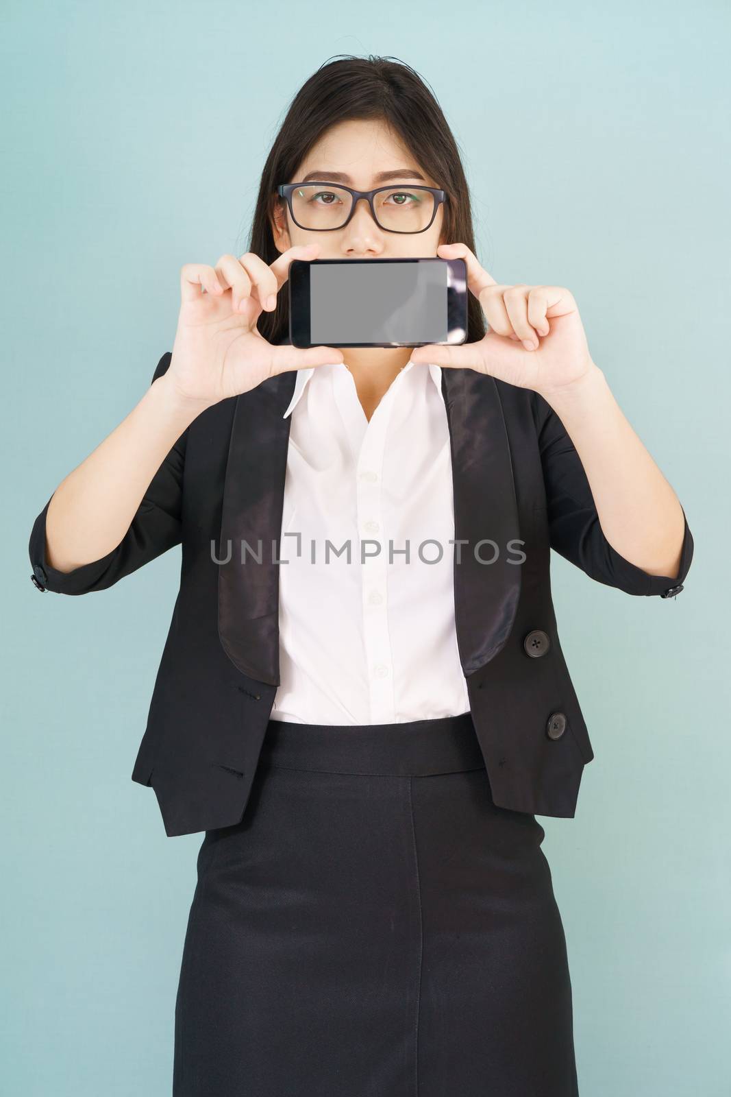 Young women in suit holding her smartphone standing against blue background