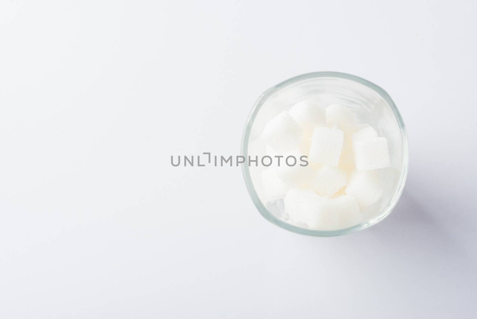 Top view glass full of white sugar cube sweet food ingredient, studio shot isolated on white background, health high blood risk of diabetes and calorie intake concept and unhealthy drink
