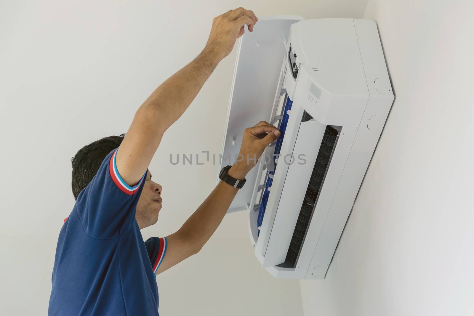 Air conditioner repairers in blue uniform are checking and repair air hanging on the wall.