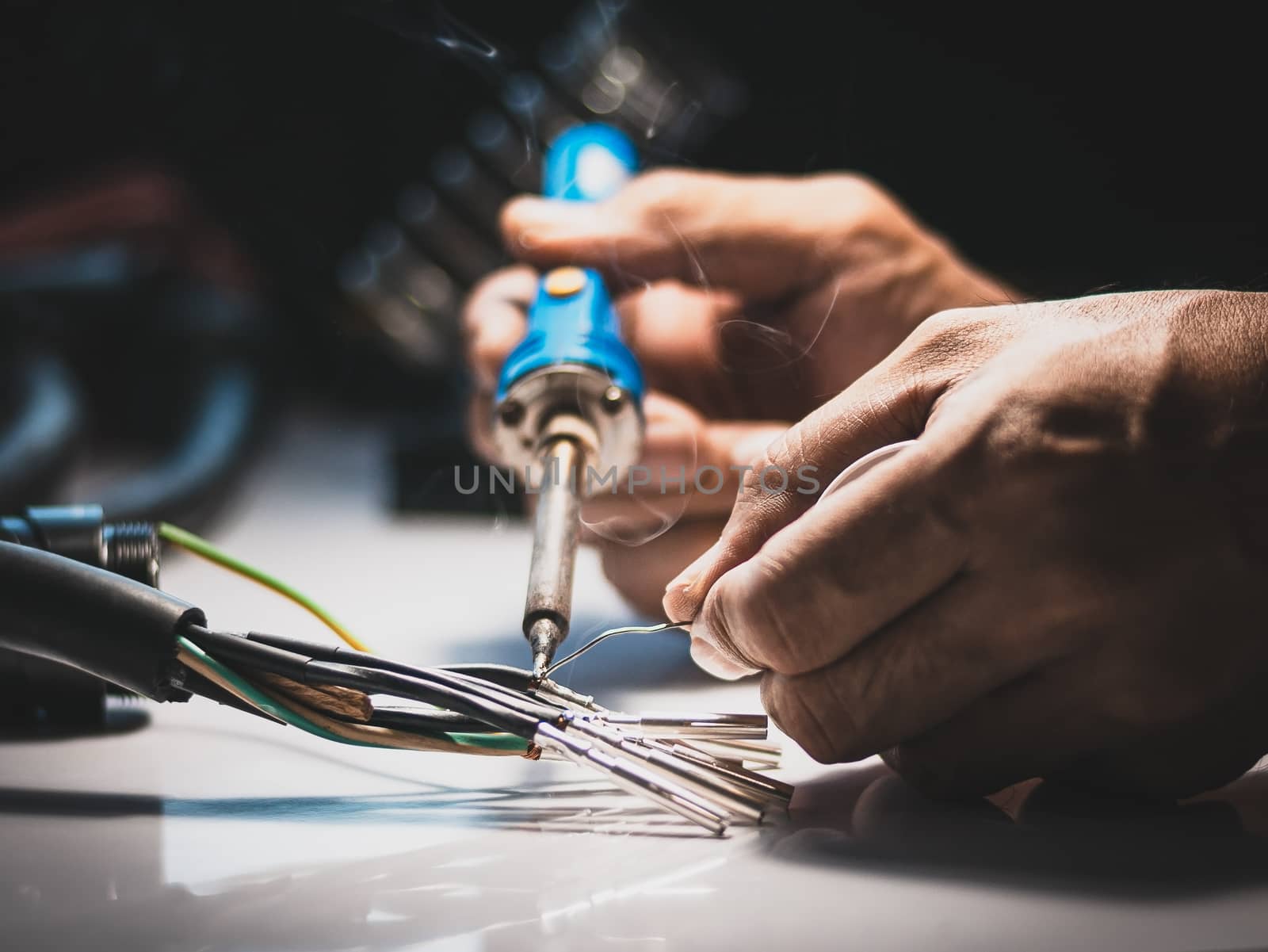 Electricians are using a soldering iron to connect the wires to the metal pin with soldering lead.