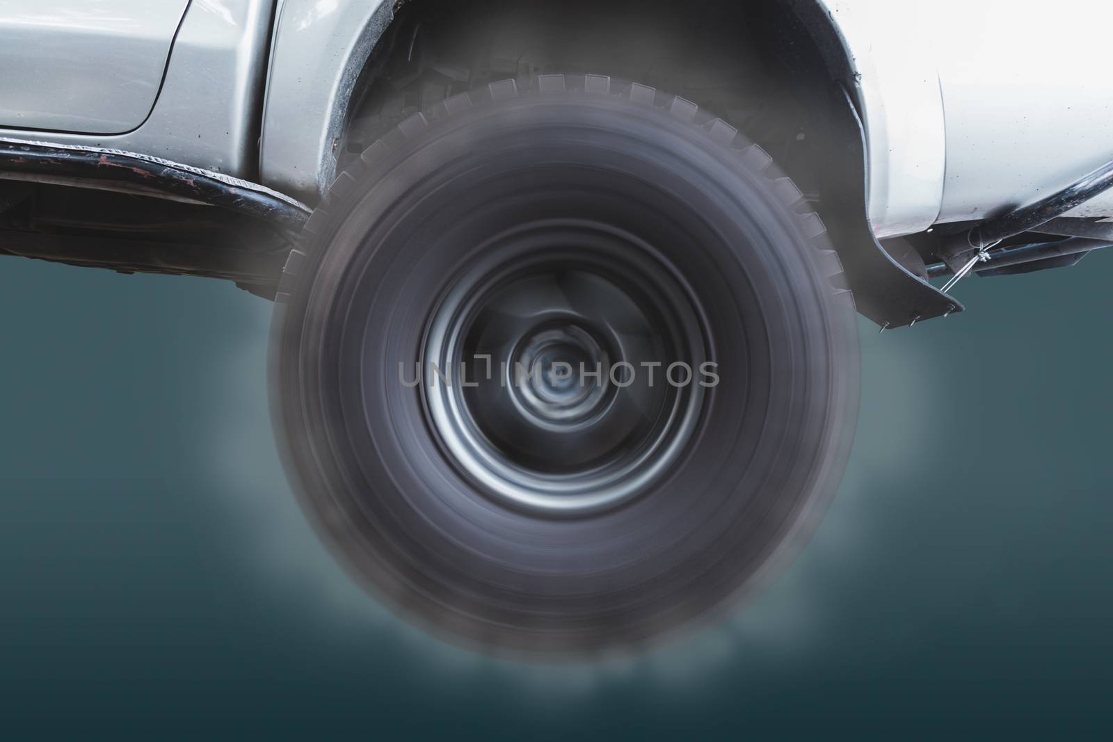 Closeup of the wheels of off-road vehicles that are rotating at high speed and with smoke coming out on pastel color background.