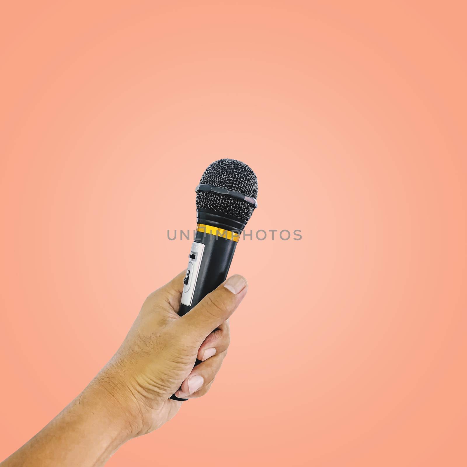 Hand holding wireless microphone isolated on pastel color background, with clipping path.