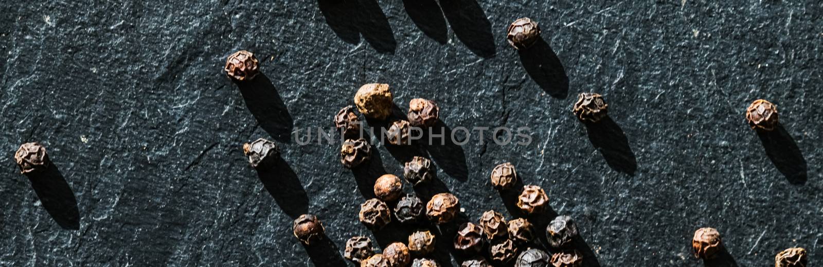 Black pepper closeup on luxury stone background as flat lay, dry food spices and recipe ingredient by Anneleven