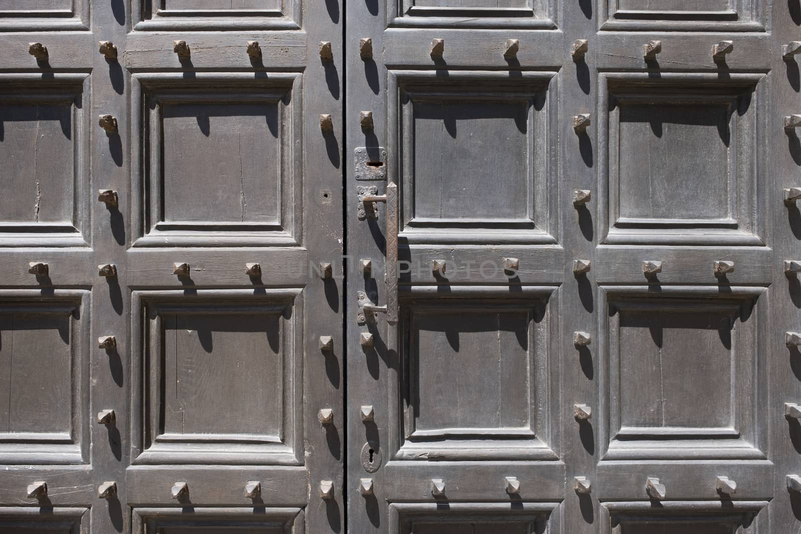 Metal spikes on old wooden door by Tjeerdkruse