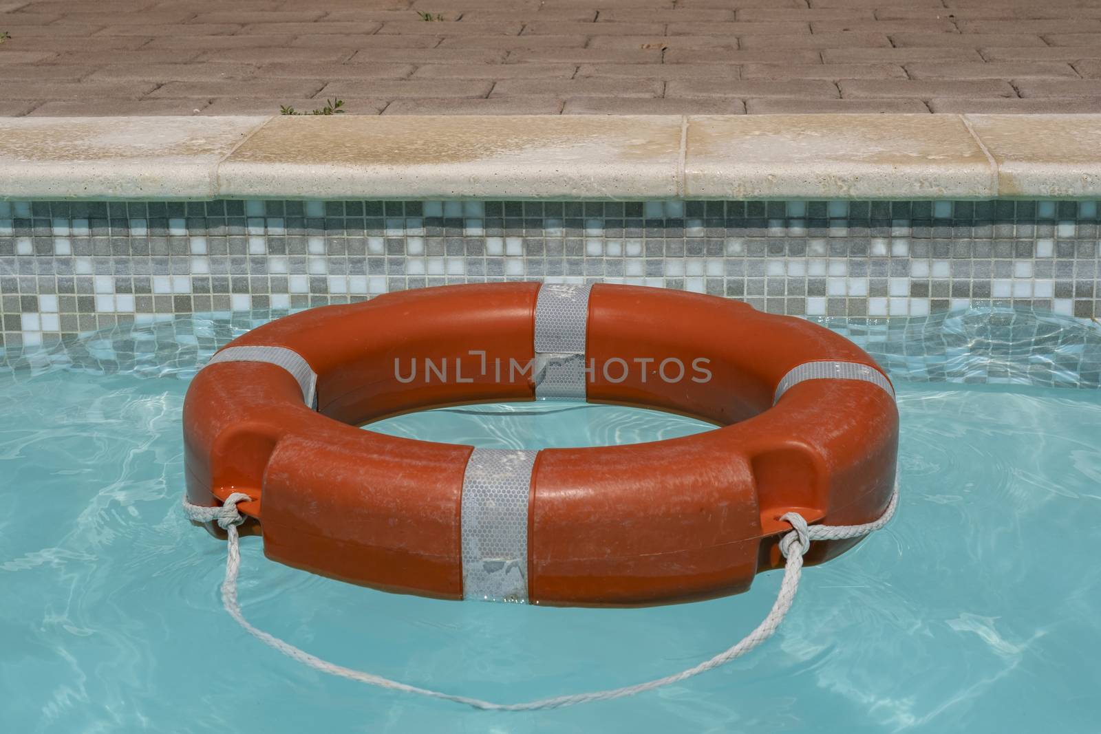 Red life buoy floating in swimming pool by Tjeerdkruse