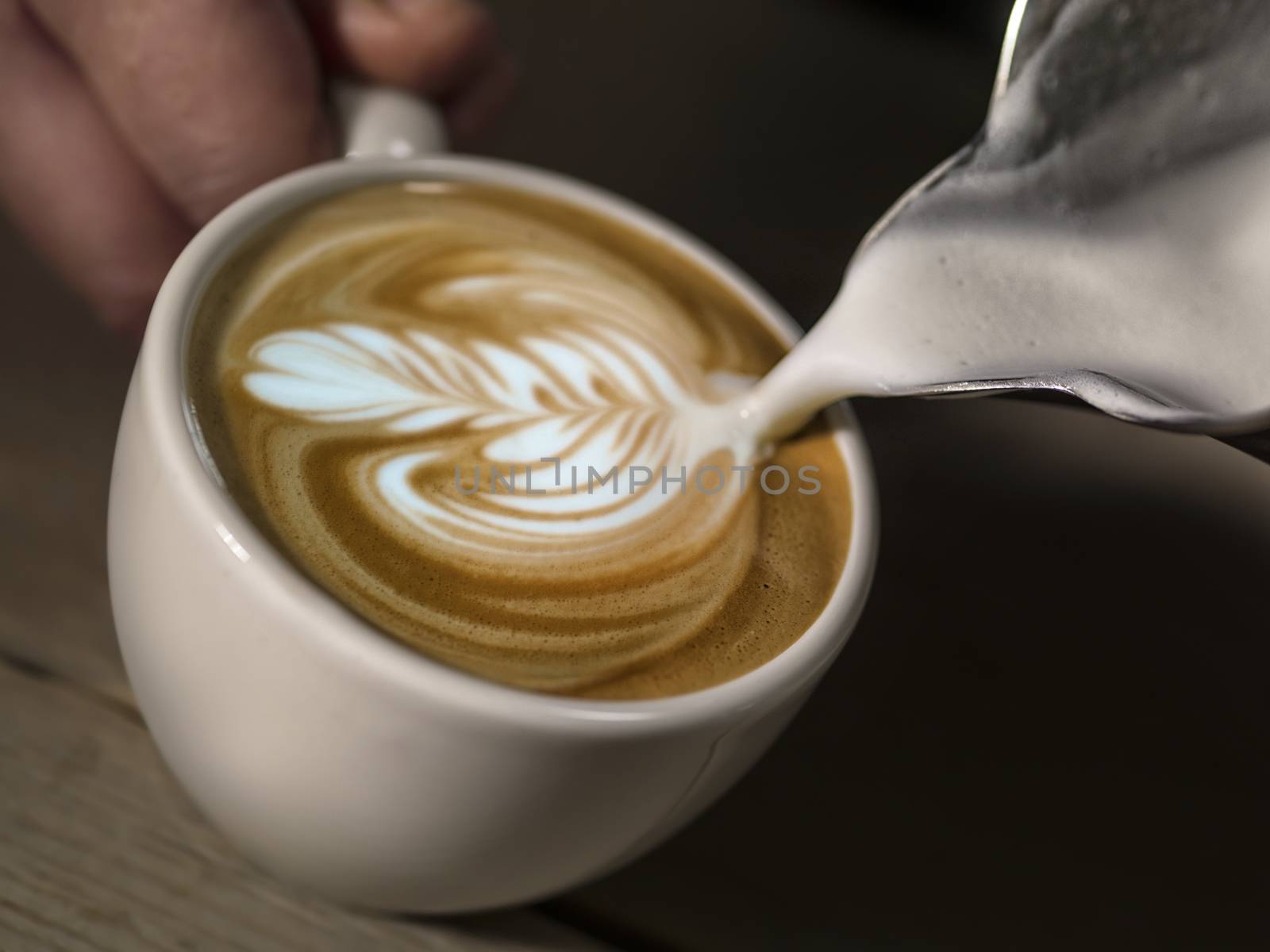 Hand on Barista making latte cafe, Cup of coffee with beautiful Latte art on a white cup