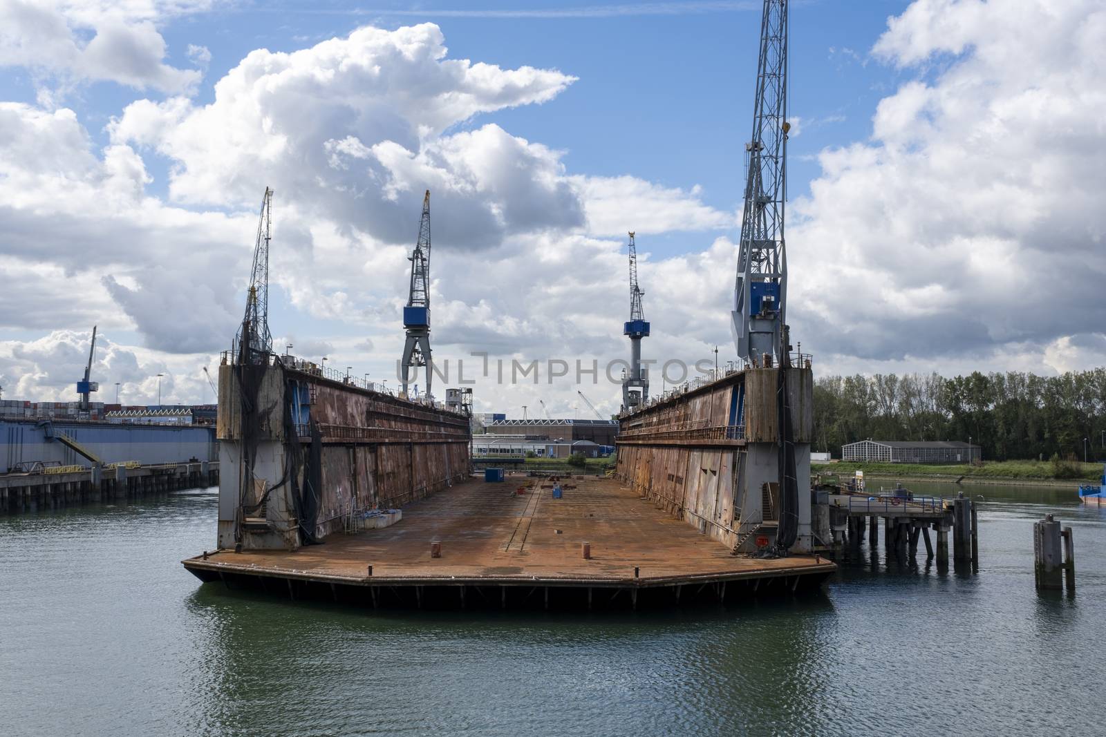Rotterdam, The Netherlands Eye level view on an empty floating dry dock with large cranes on the side by Tjeerdkruse