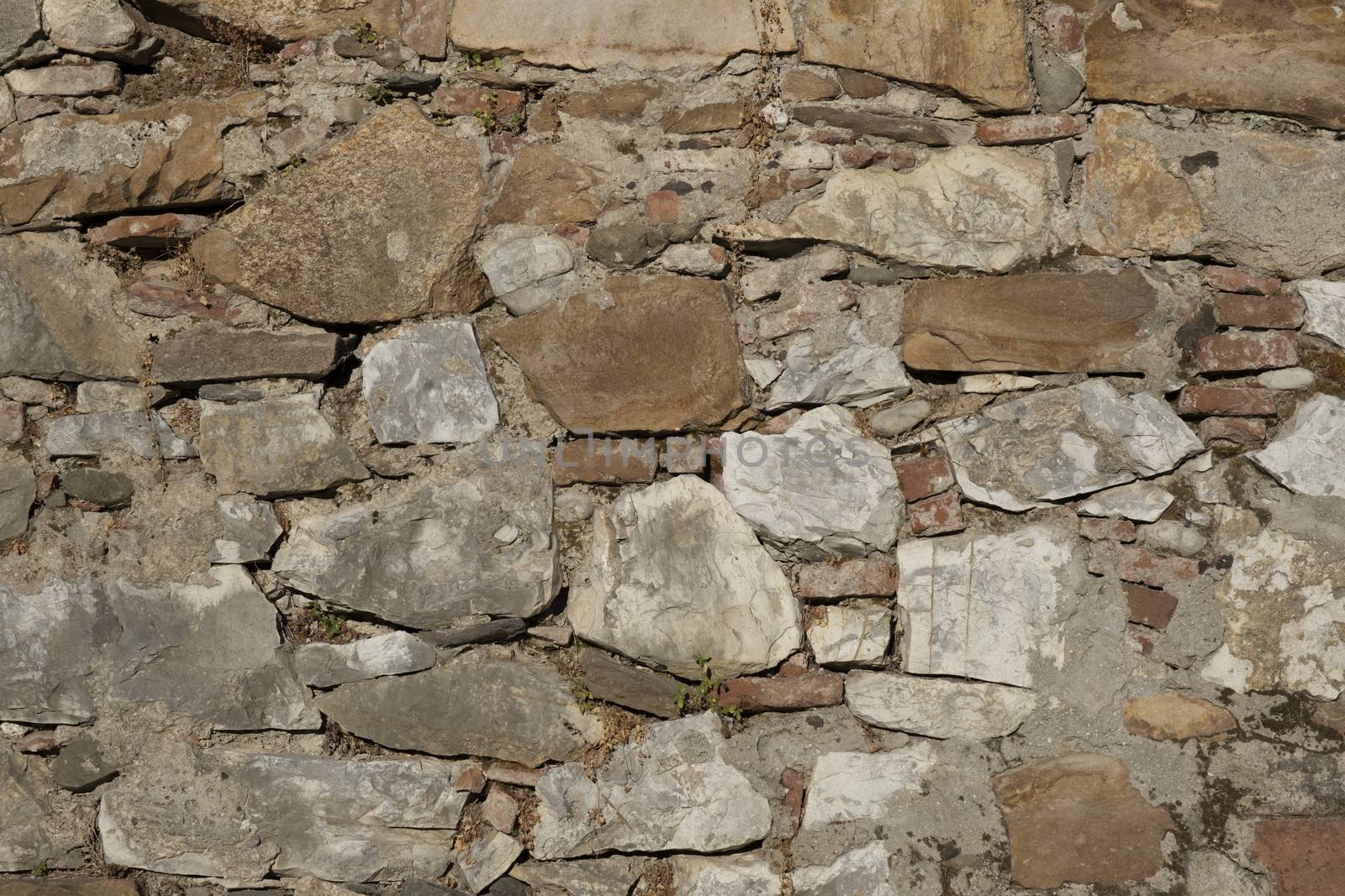 Wall texture of ancient old brick stone. Outdoor exterior castle facade with destroyed uneven pattern of shabby rock. Solid wall sandstone structure background. Grunge surface useful for 3d texturing