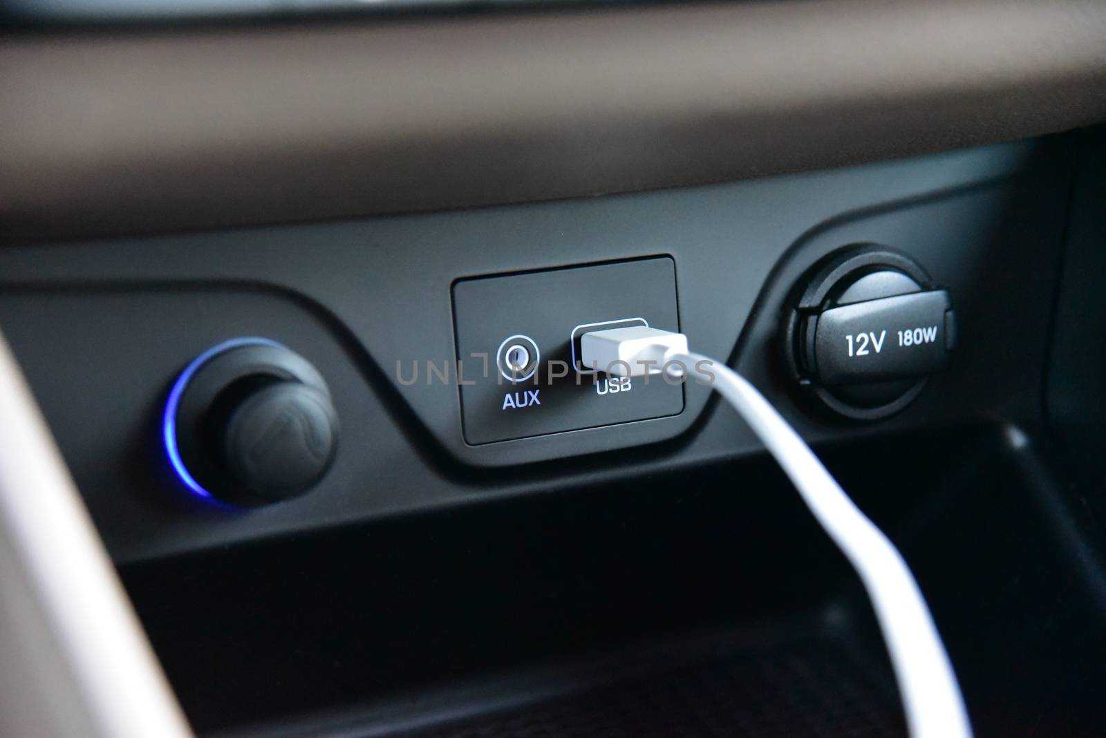 Vehicle interior view of a connected USB cable to a USB port in car dashboard with selective focus