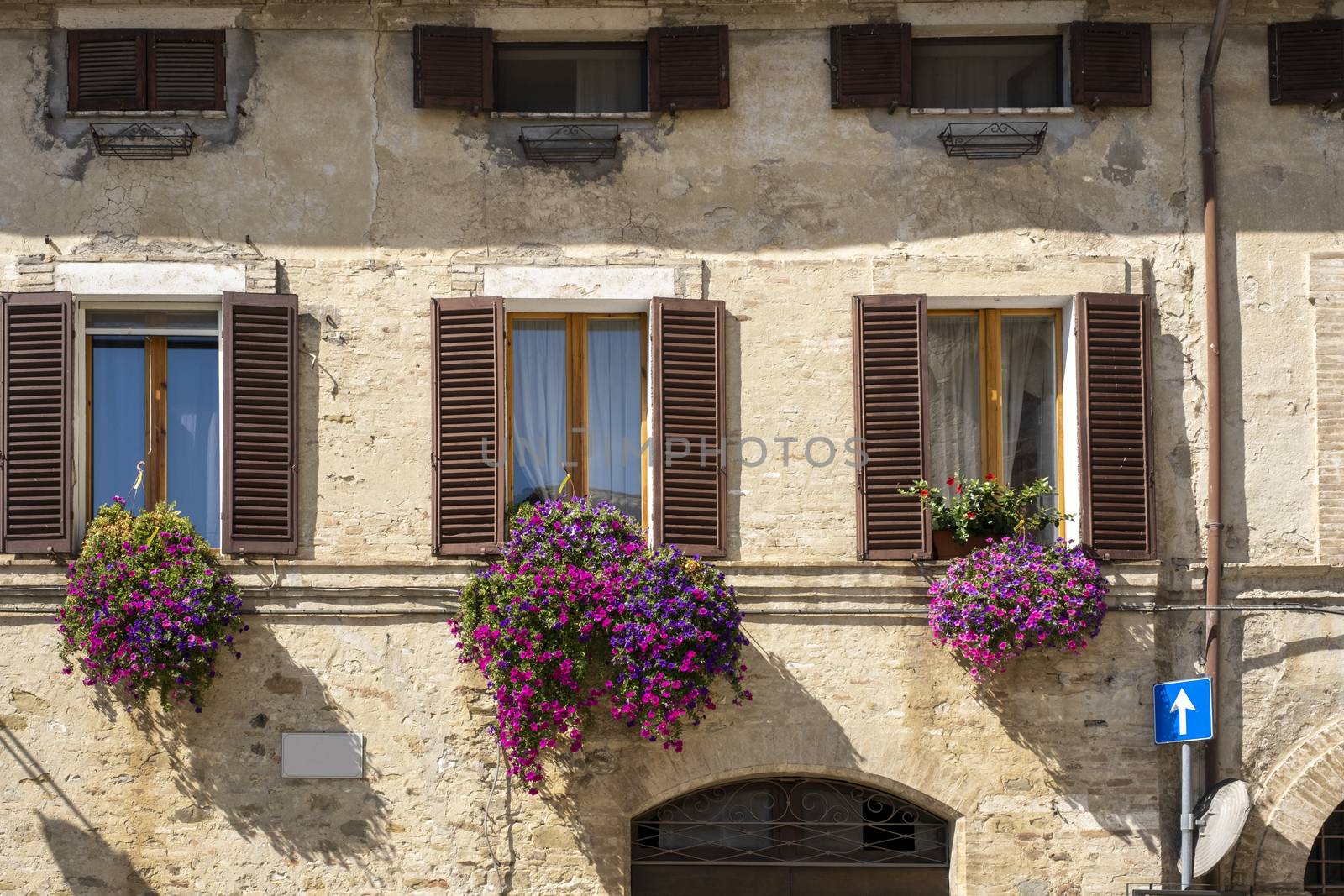 Vintage windows with open wooden shutters and fresh flowers in Italy