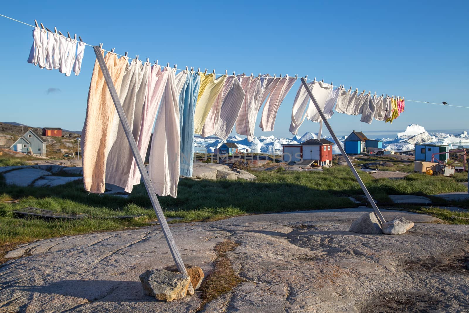 Rodebay, Greenland - July 9, 2018: A clothes line with colorful houses and icebergs in the background.