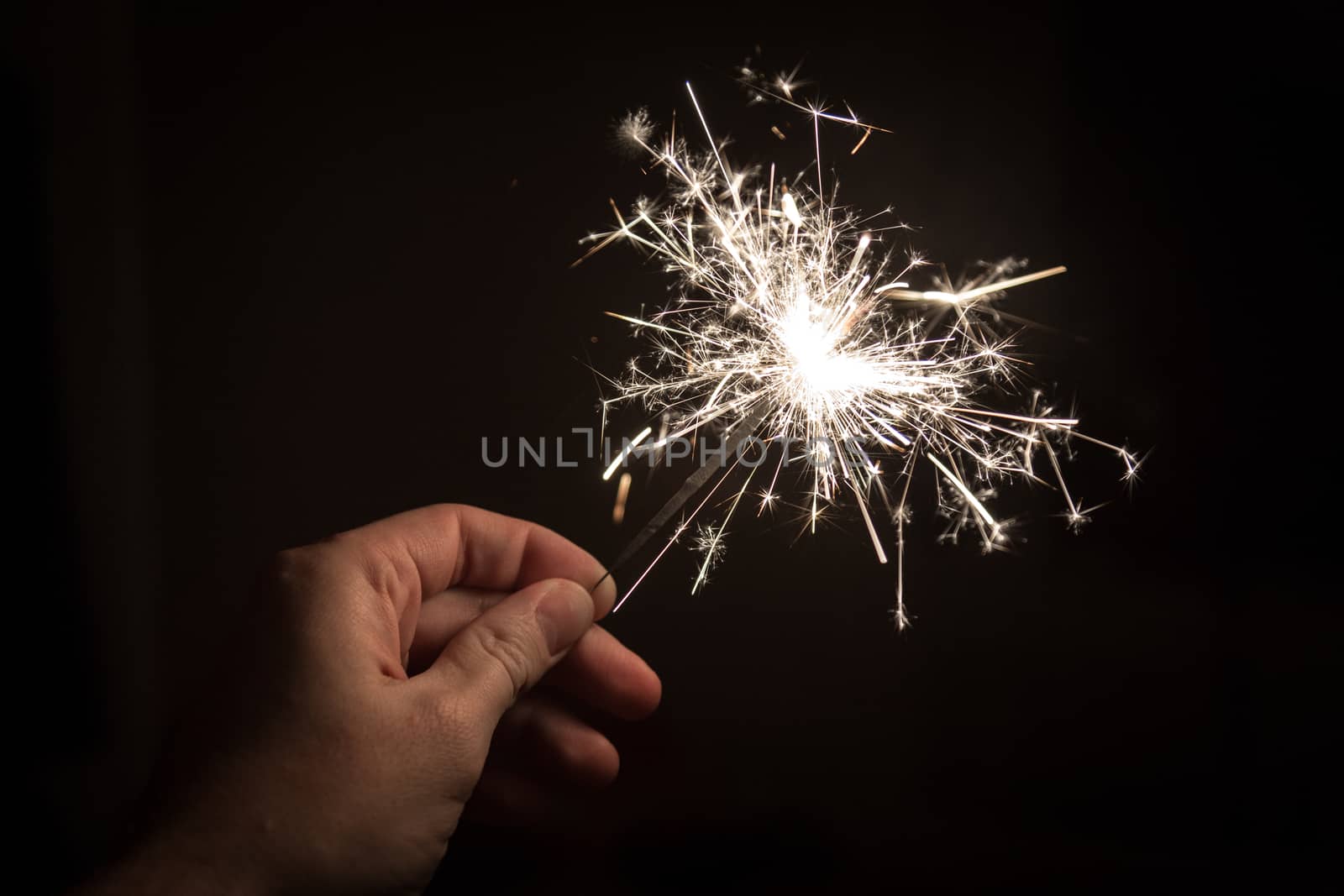 A hand holding a sparkler on a black backgournd