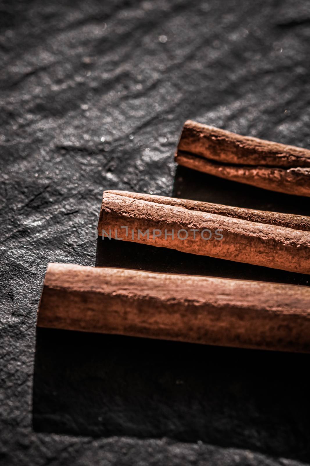 Cinnamon sticks on black stone background, food recipe by Anneleven