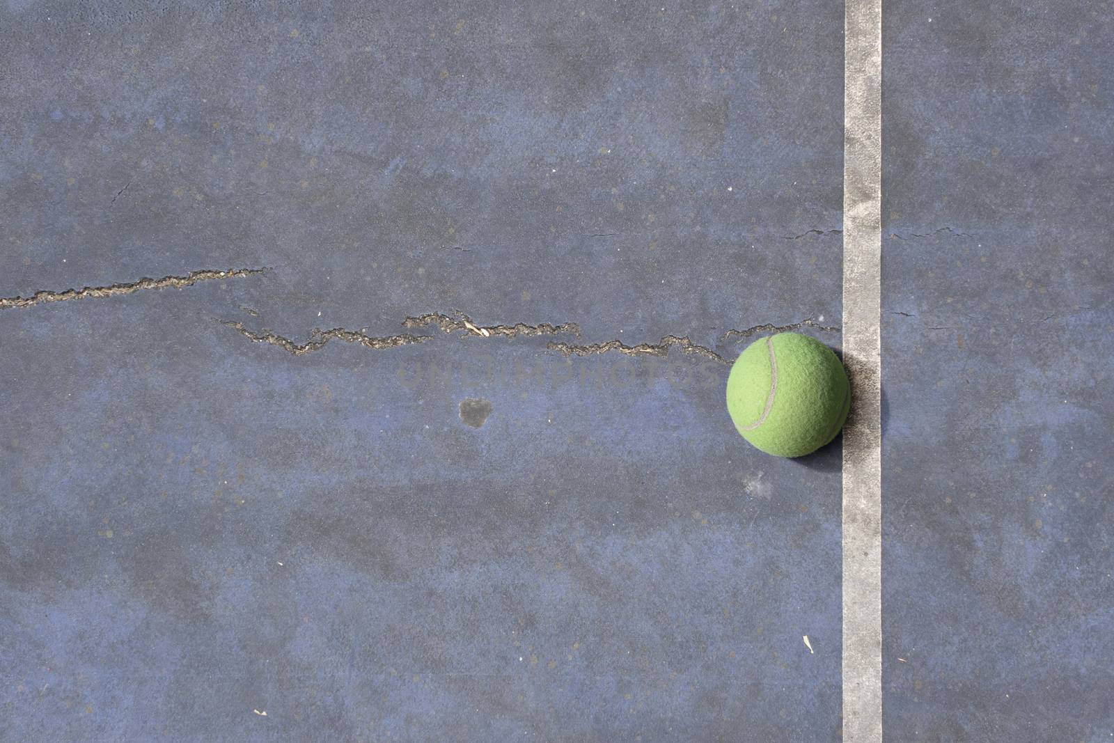 Tennisball on a blue rundown tennis court by Tjeerdkruse