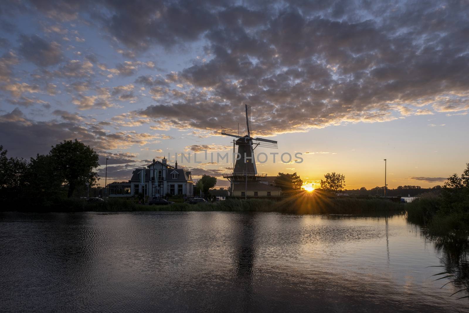 Sundown with Dutch windmill in the waters of Kralingse Plas, Rotterdam by Tjeerdkruse