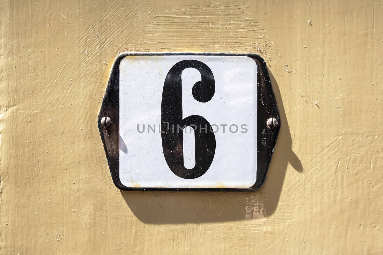 Number 6 in white on a black metal plate by Tjeerdkruse