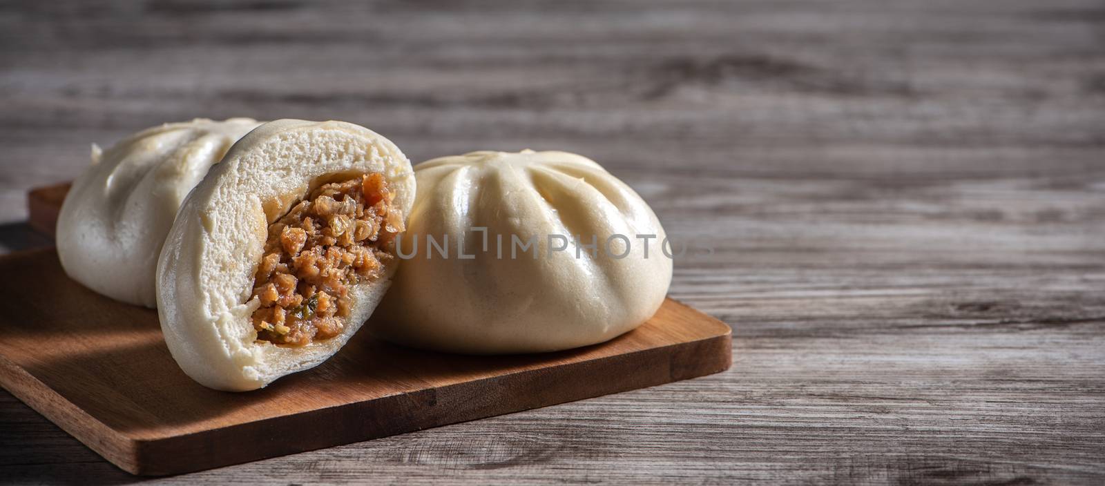 Delicious baozi, Chinese steamed meat bun is ready to eat on serving plate and steamer, close up, copy space product design concept.