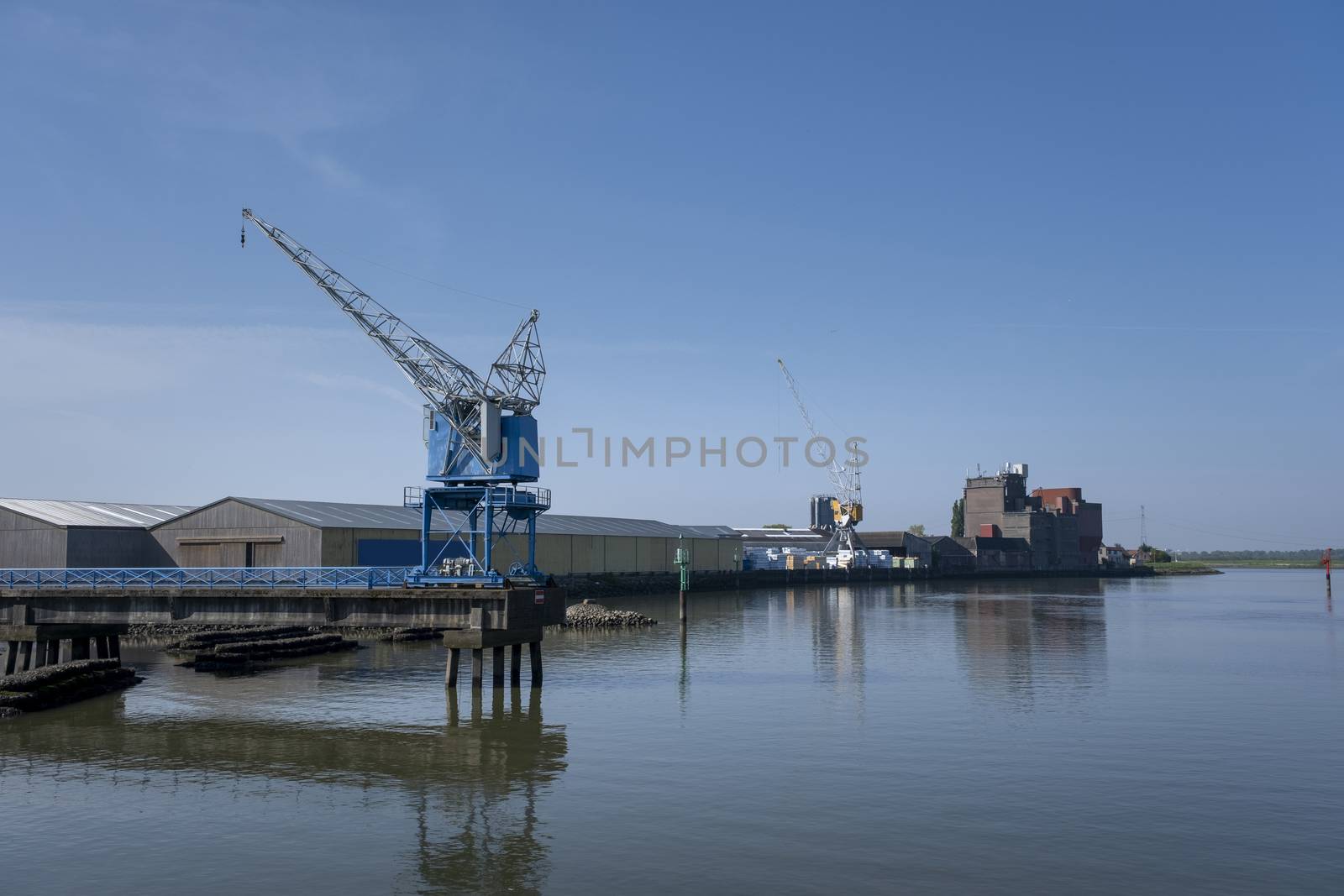 Cranes near the river against blue sky. Industrial landscape, industrial zone.