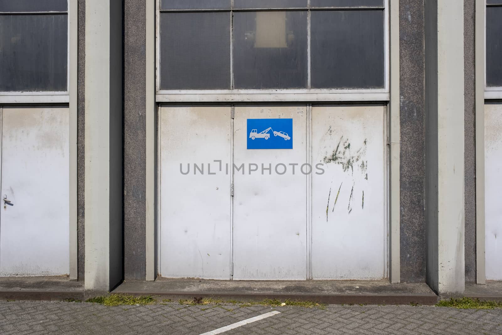 old metal warehouse door, hangar with tow away sign by Tjeerdkruse