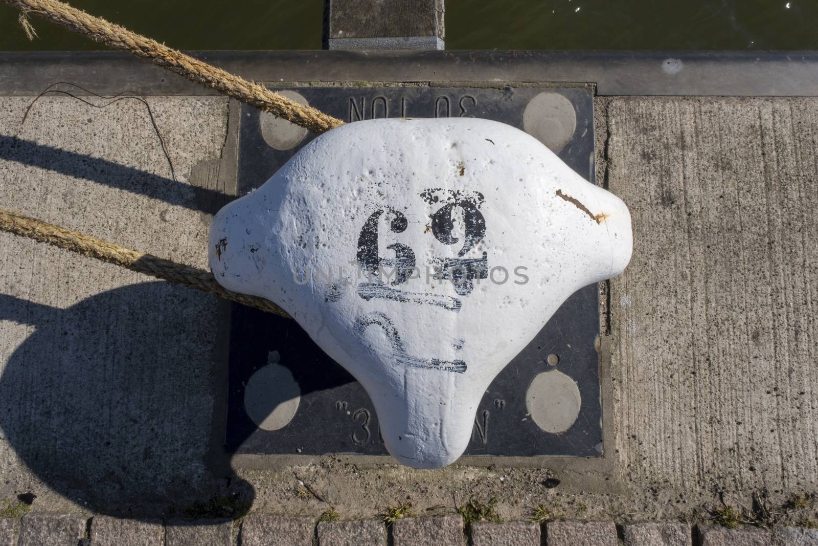 Metal white bollard from Rotterdam harbour with number sixty-two by Tjeerdkruse