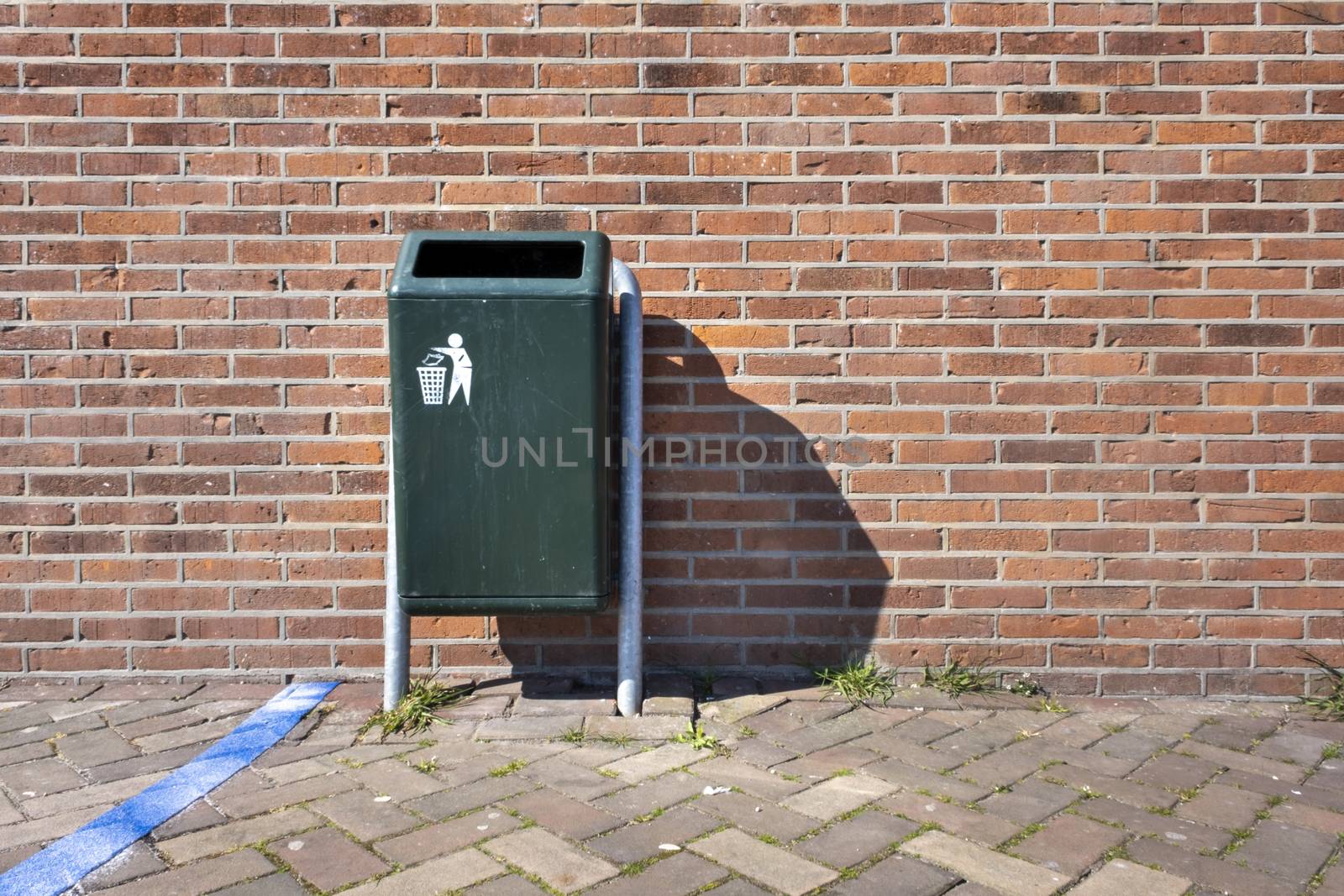 Modern green Metallic trash bin in a sunny urban environment