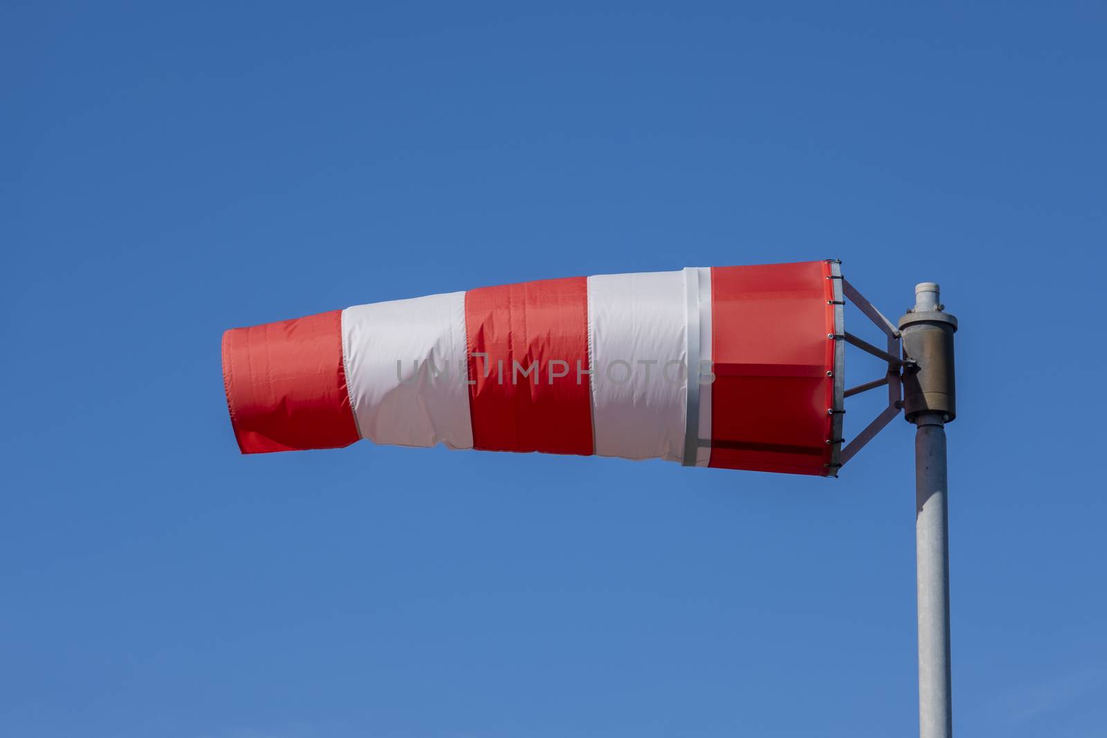Windsock indicator of wind on runway airport. Wind cone indicating wind direction and force. Horizontally flying windsock (wind vane) with blue sky in the background