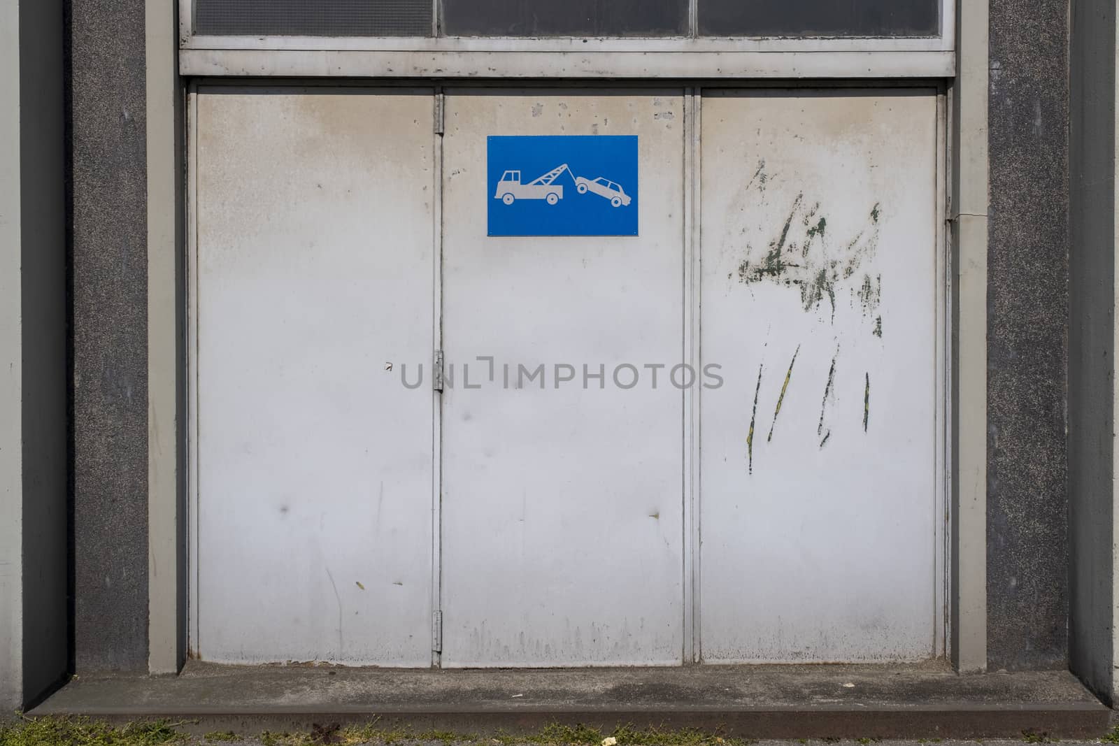 old metal warehouse door, hangar with tow away sign by Tjeerdkruse