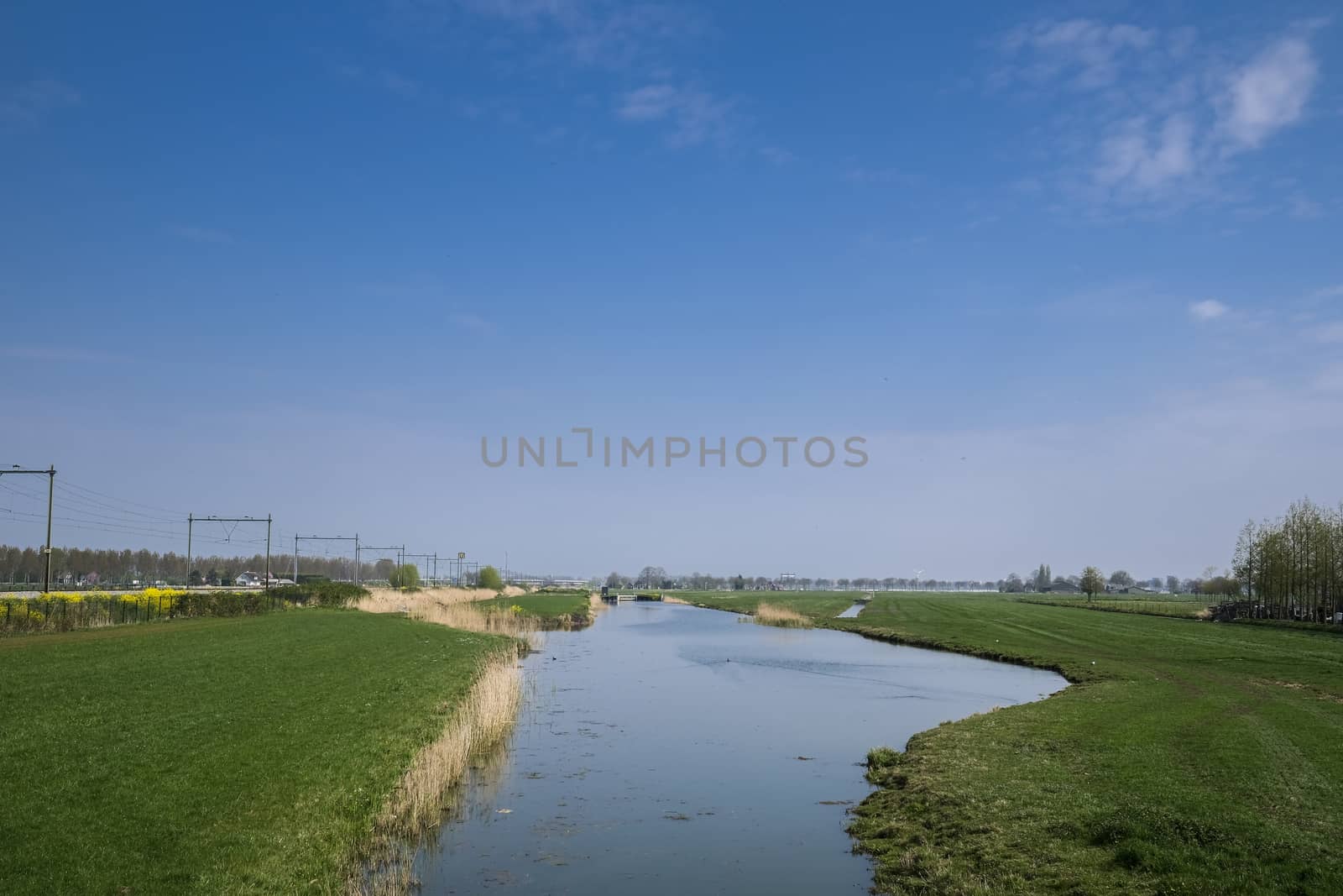 Dutch polder landscape in the spring season with a train track o by Tjeerdkruse