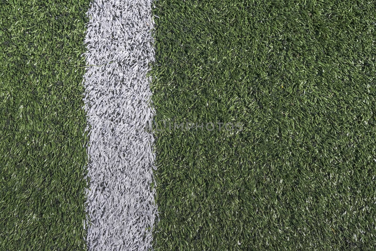 White stripe on a bright green artificial grass soccer field by Tjeerdkruse