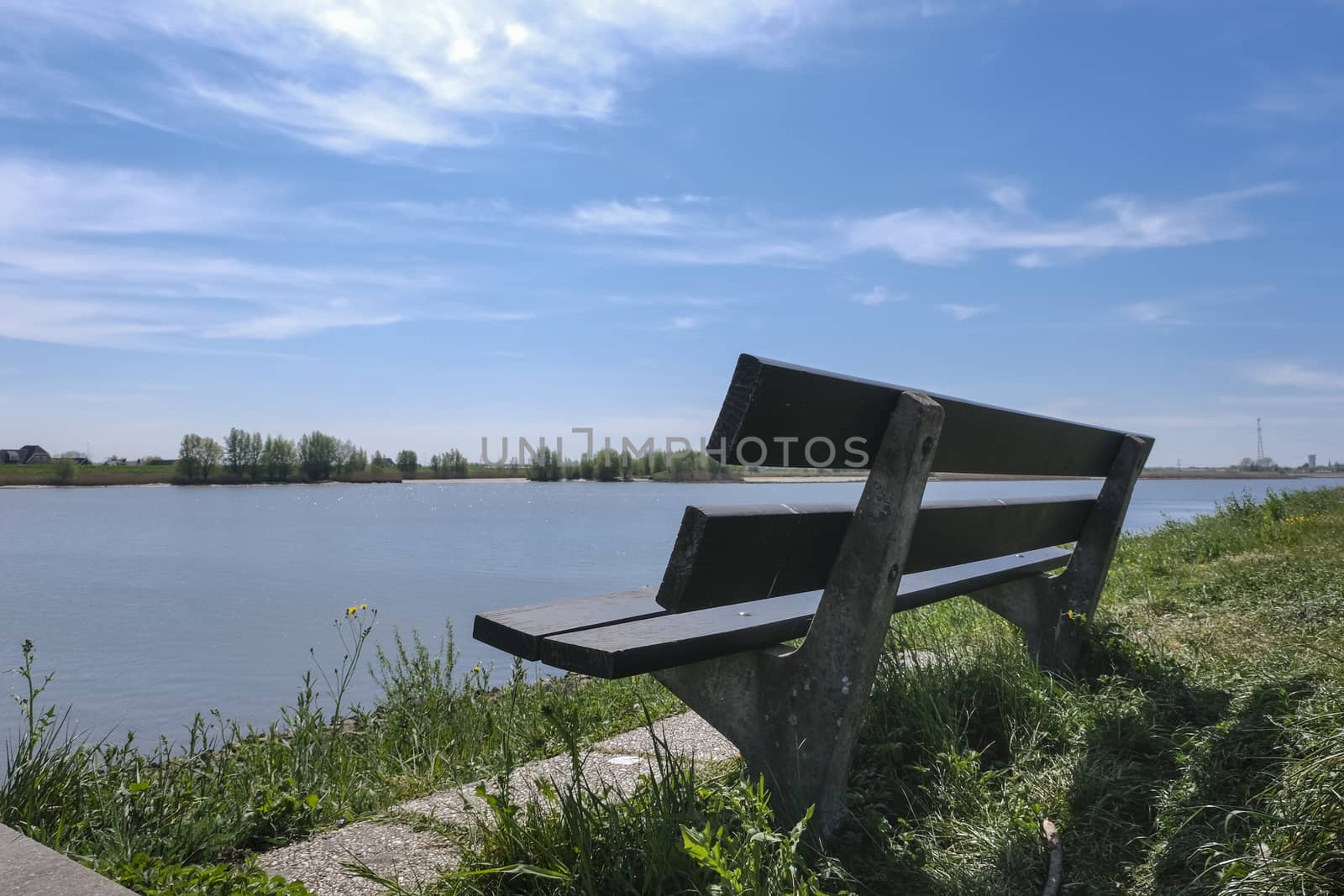 River shore and empty bench. Summer landscape of a river with ca by Tjeerdkruse