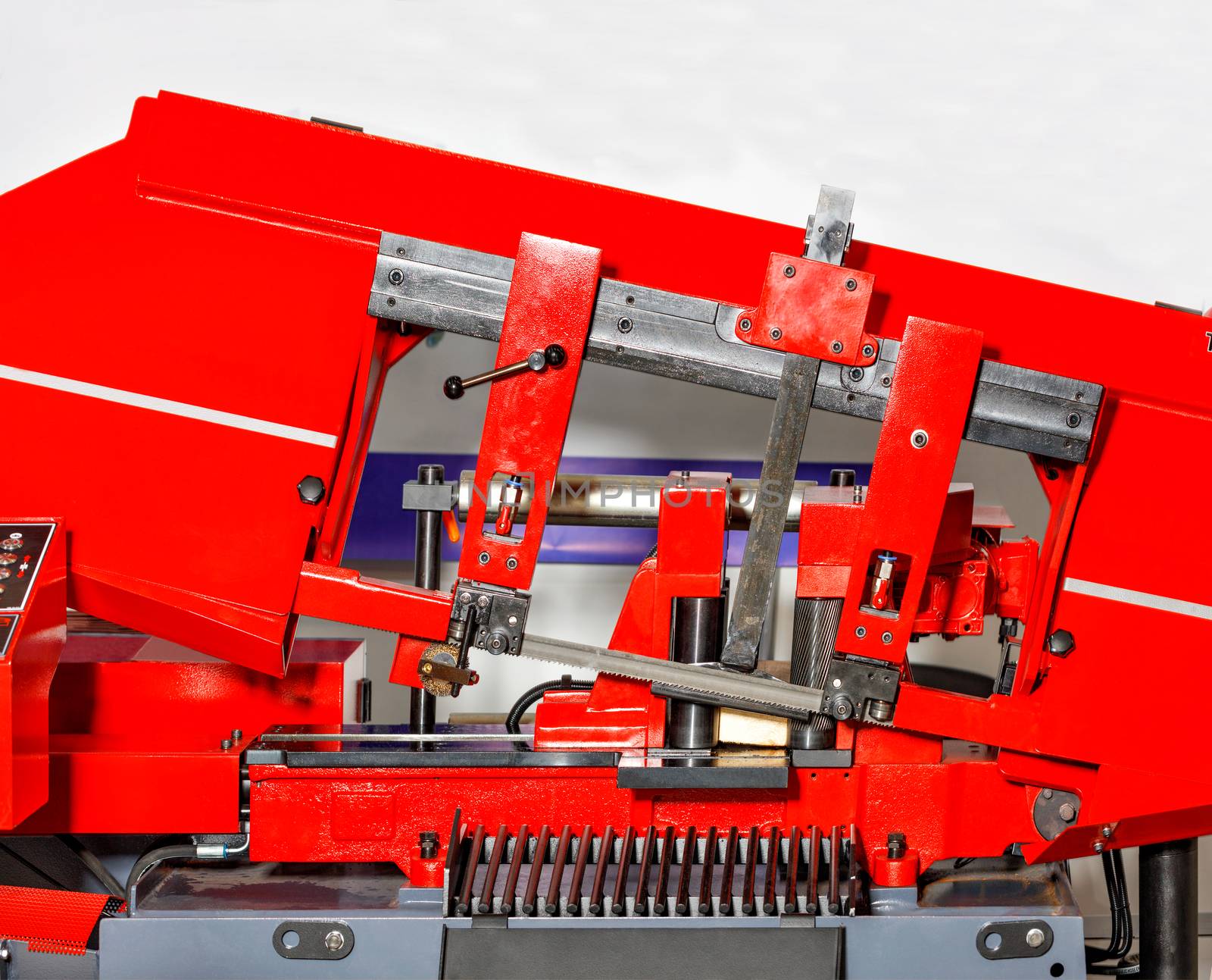 A modern metal cutting machine with bright red color with sharp teeth of the band saw provides high cutting accuracy due to the control line. Copy space.