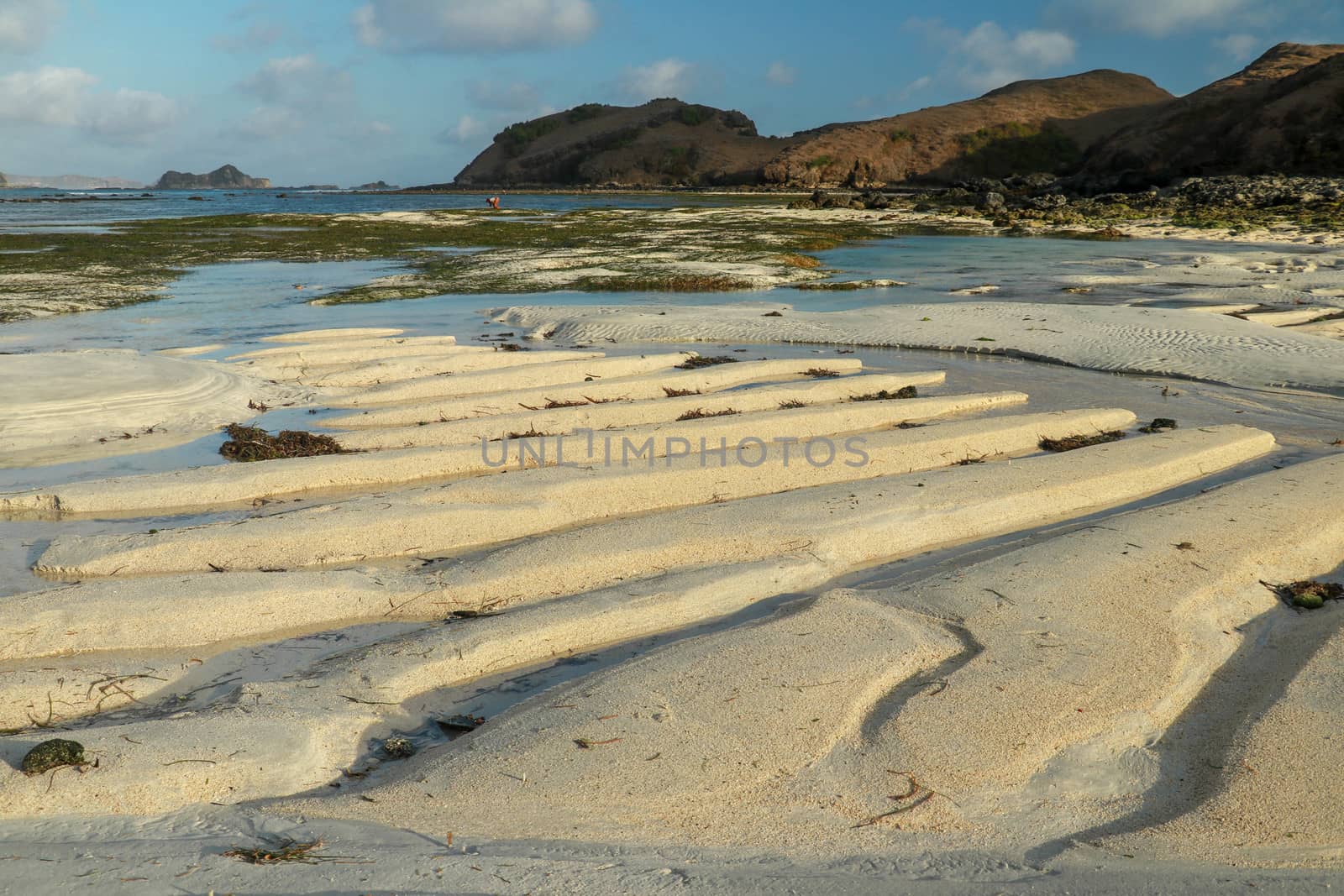 Foreground focus of sand dune during sunrise with light reflection above sea at quiet and peaceful beach. Tropical beach sand dune when sea water is low tide.