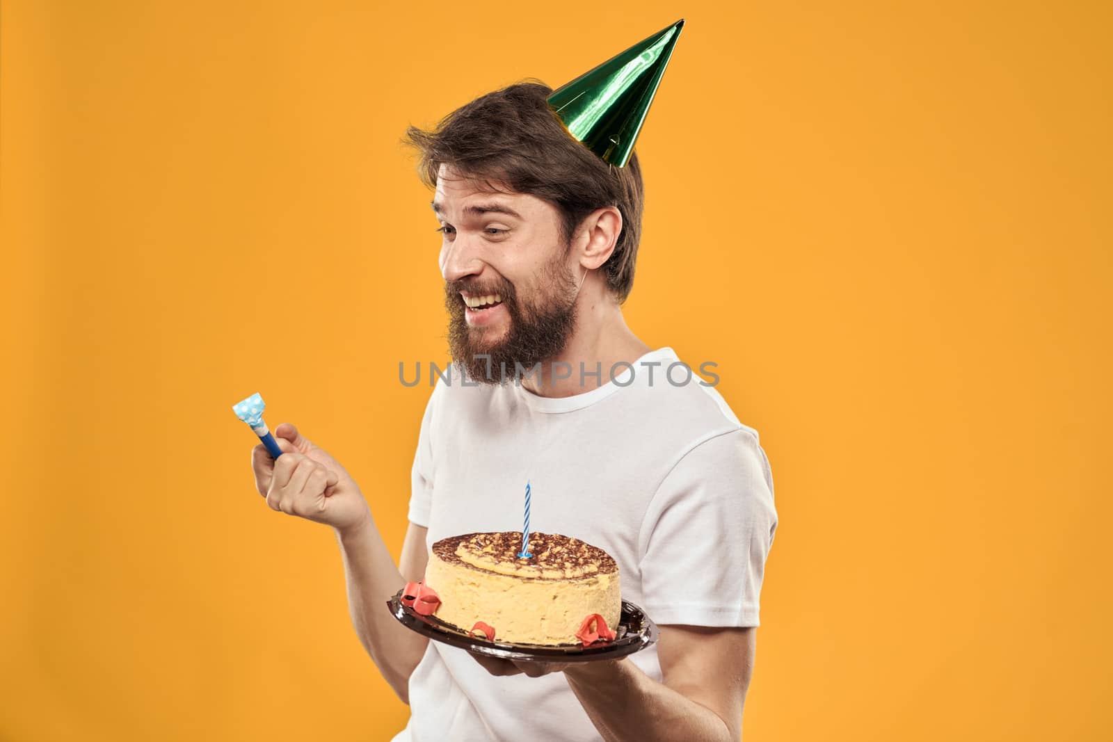 birthday boy in a cap with cake fun yellow background party. High quality photo