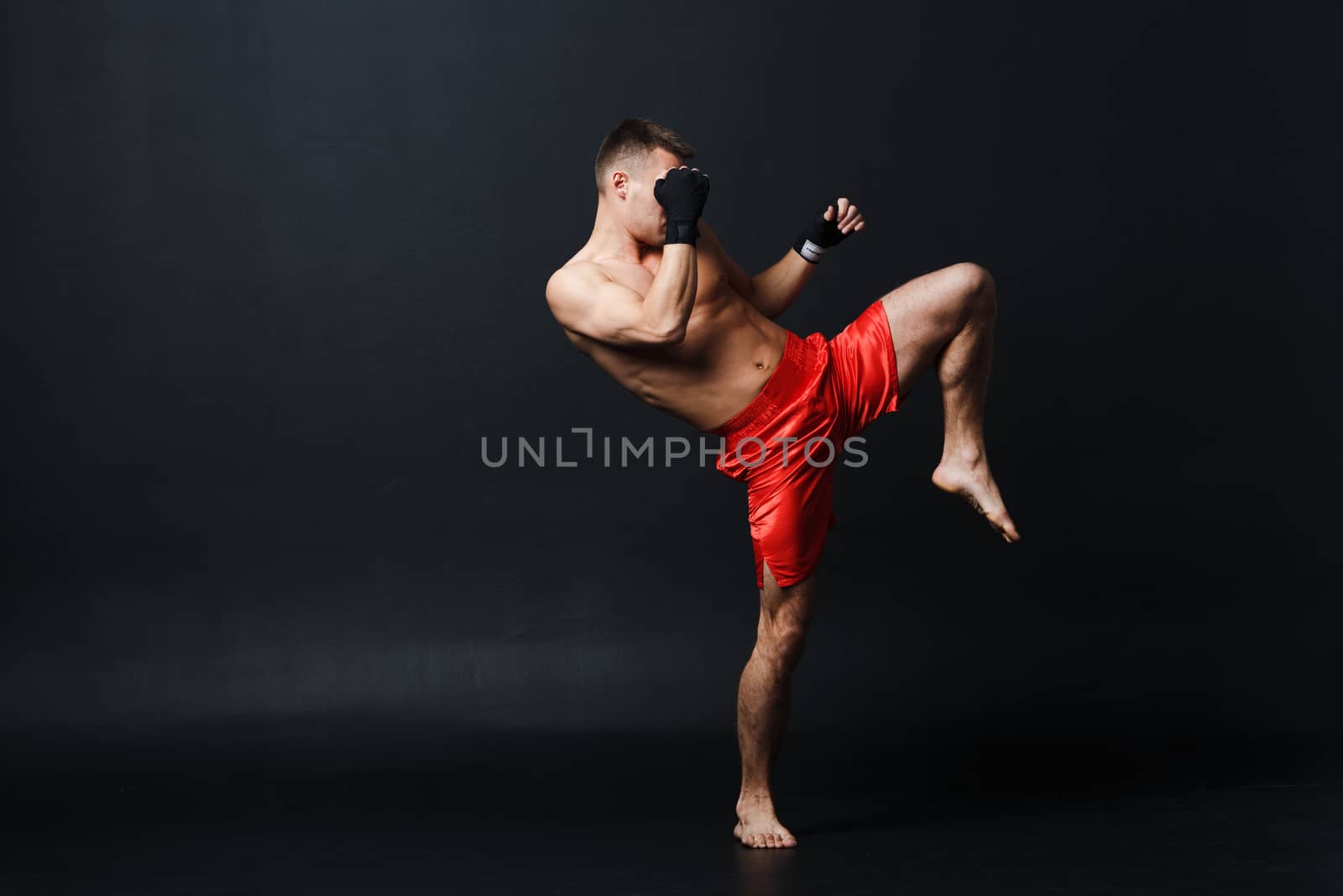 Sportsman muay thai man boxer stance ad knee kick at black background by primipil