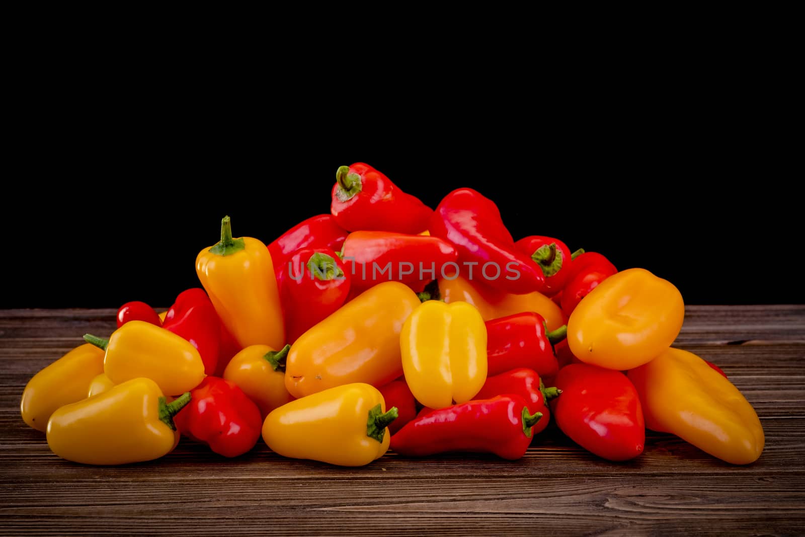 Fresh colored bell peppers on a wooden table on a rustic wooden background, selective focus