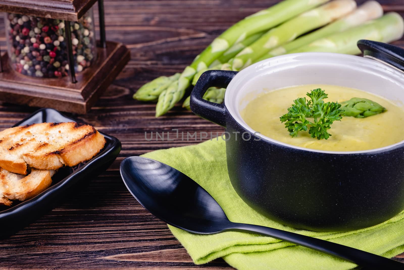 Fresh asparagus creamy soup and ingredients on a wooden table. by Fischeron