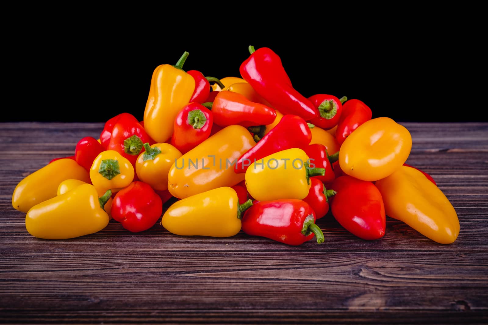 Fresh colored bell peppers on a wooden table on a rustic wooden background, selective focus