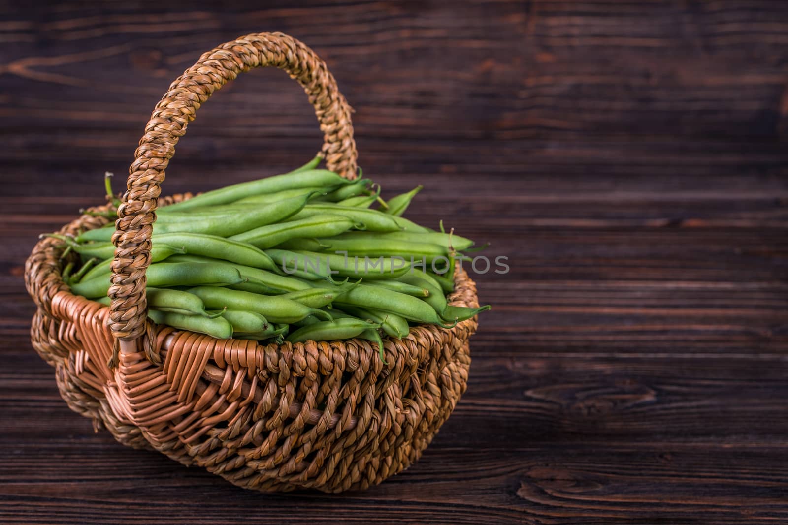 Fresh green beans on wooden table on rustic wooden background, selective focus