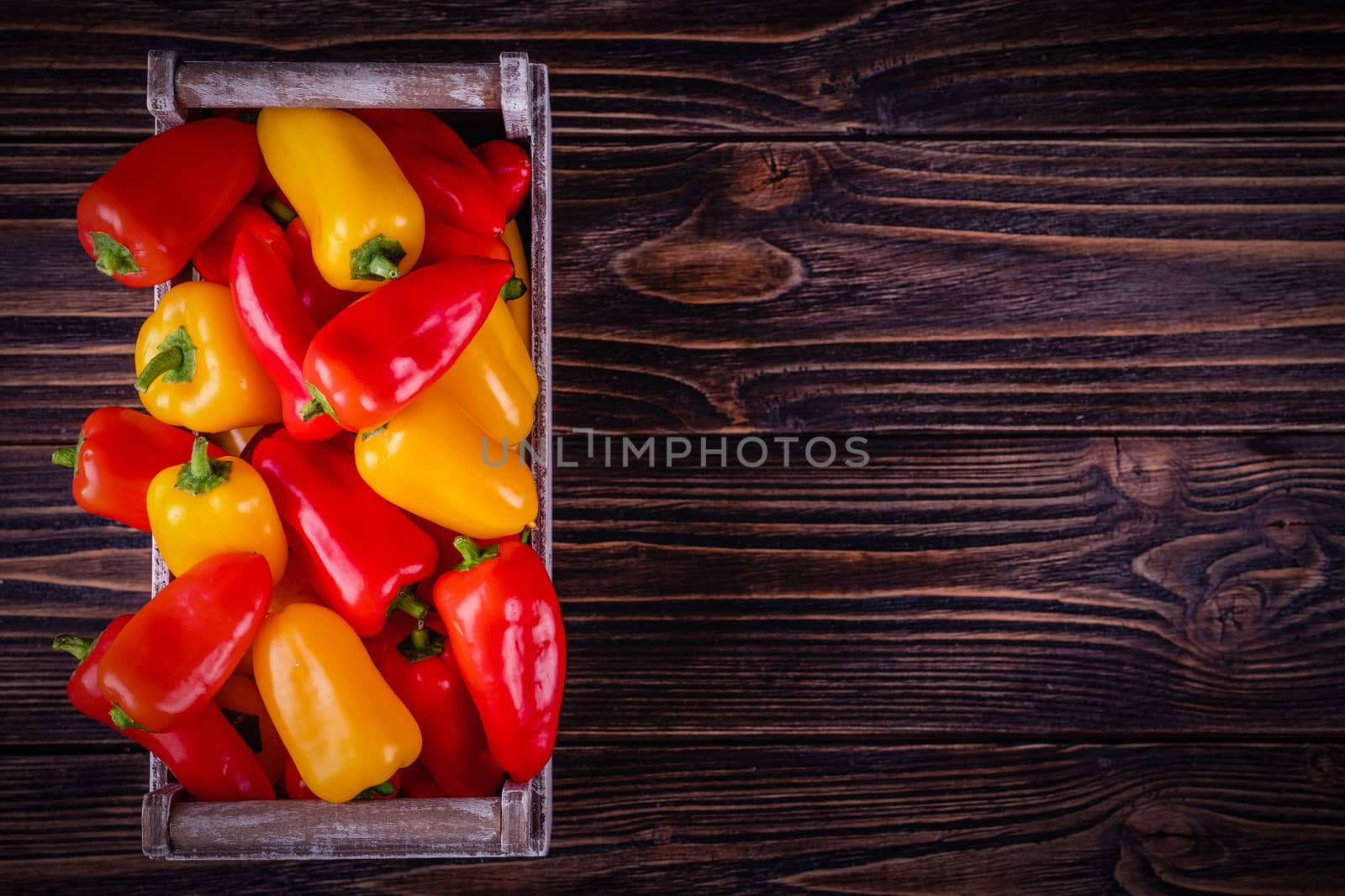 Fresh colored bell peppers on a rustic wooden background. by Fischeron