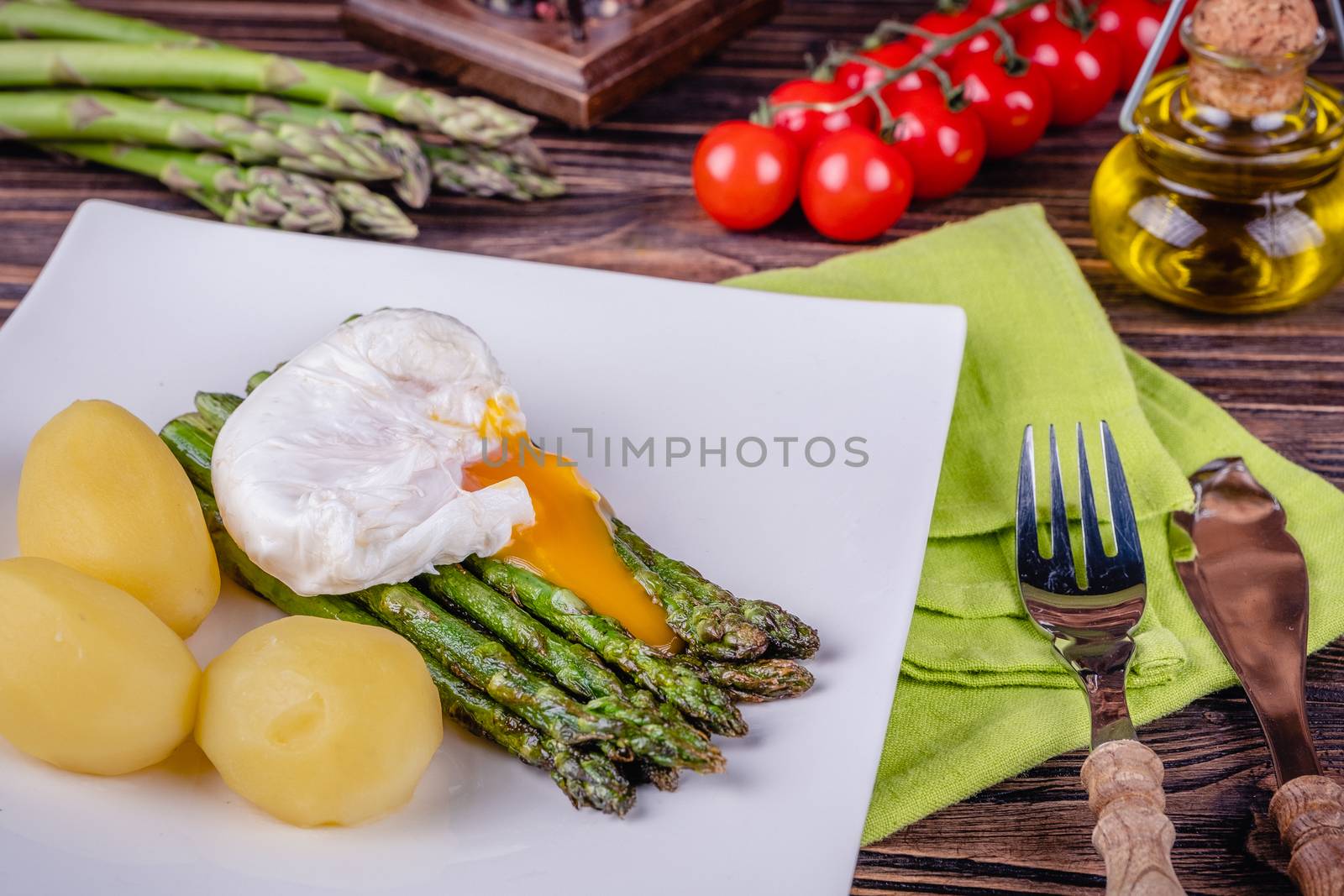 Green asparagus and boiled poached egg on a white plate. by Fischeron