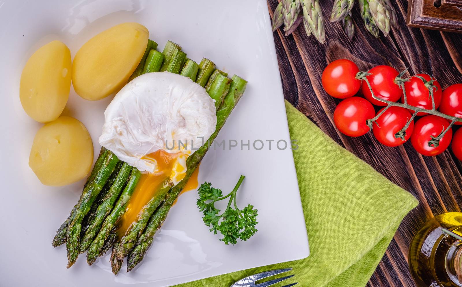 Green asparagus and boiled poached egg on a white plate. by Fischeron