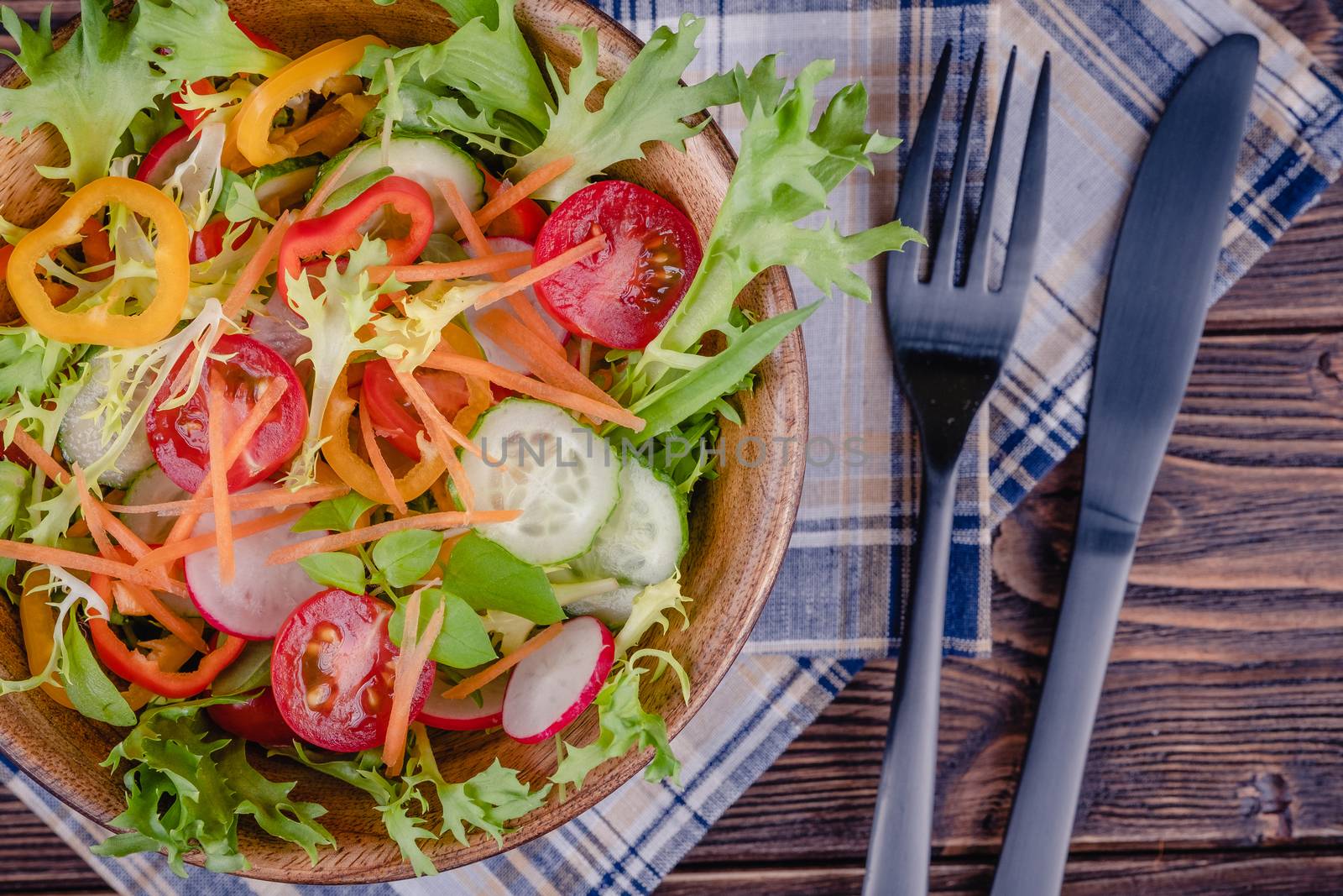 Fresh chopped vegetables on a plate on a wooden table on a rustic wooden background, selective focus