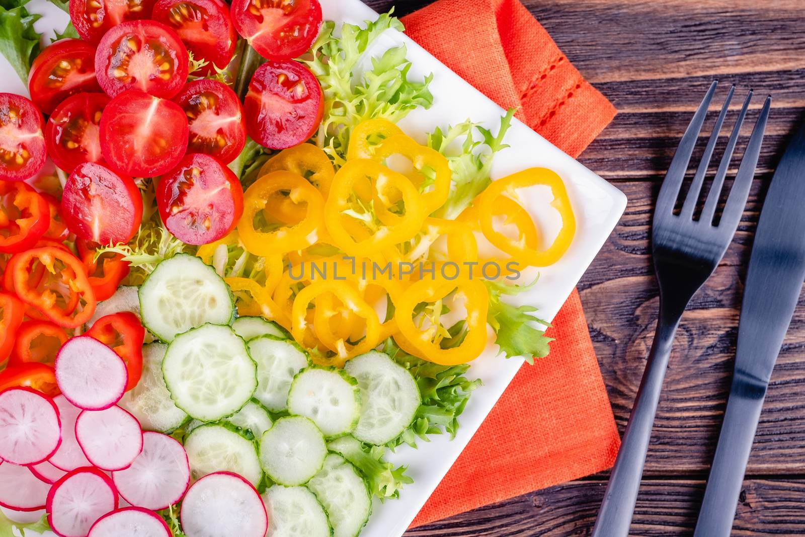 Fresh chopped vegetables on a plate on a wooden table on a rustic wooden background, selective focus