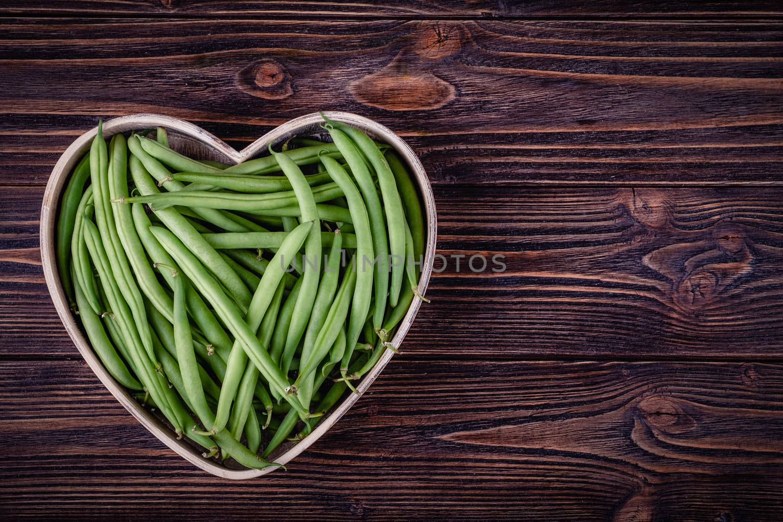 Fresh green beans on wooden table on rustic wooden background by Fischeron