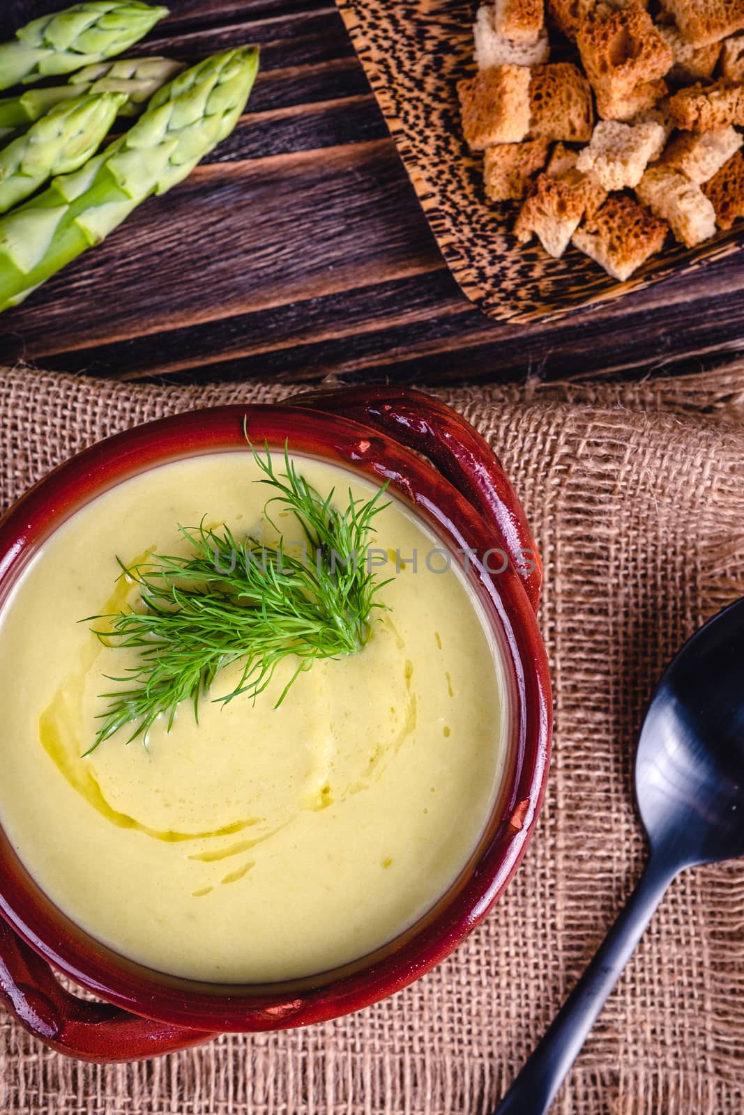 Fresh asparagus creamy soup and ingredients on a wooden table. by Fischeron