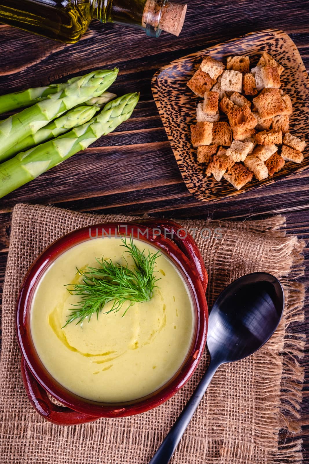 Fresh asparagus creamy soup and ingredients on a wooden table. by Fischeron