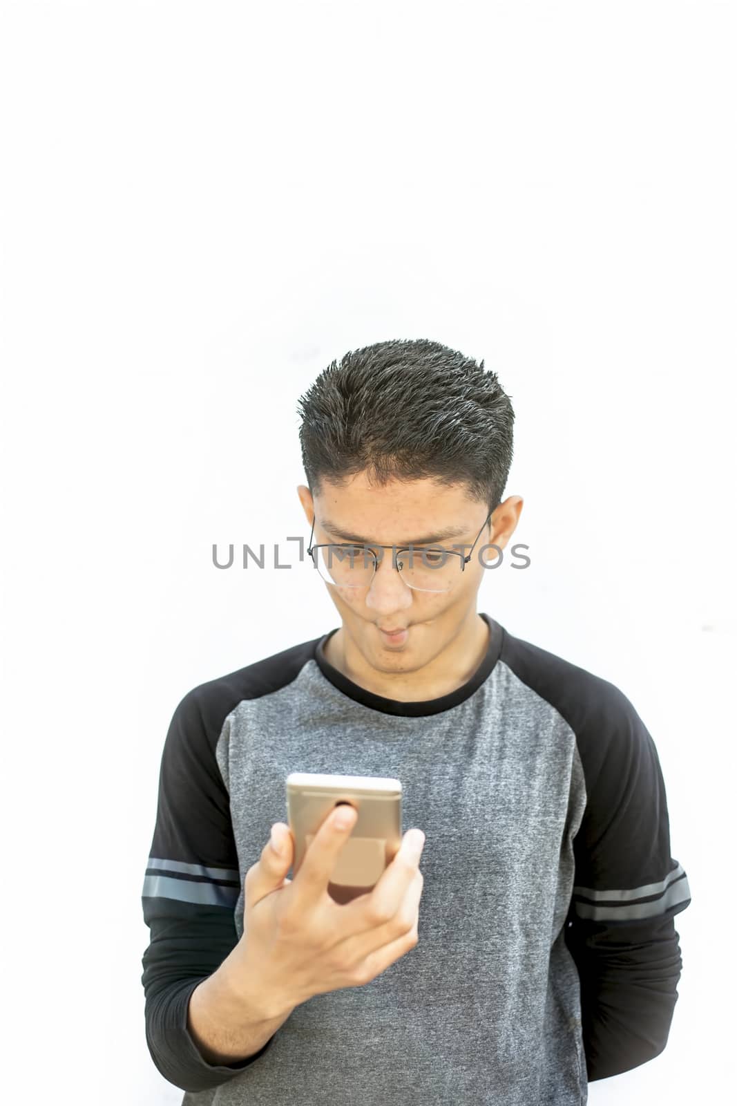Portrait shot of young Caucasian white male teenager isolated on white using smart phone.