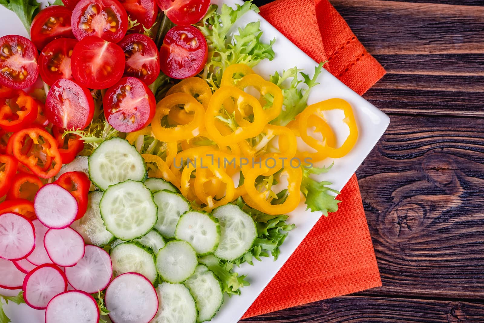 Fresh chopped vegetables on a plate on a wooden table. by Fischeron